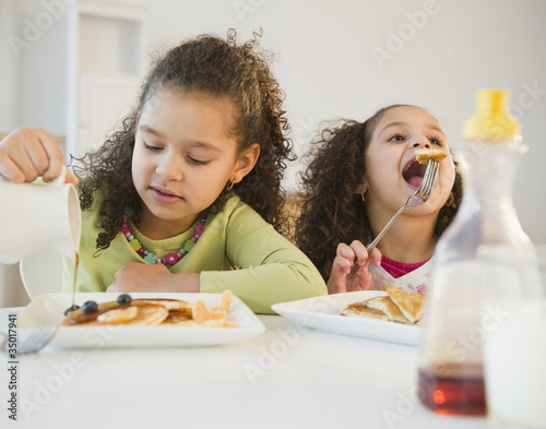 Photo: Hispanic sisters eating pancakes Hispanic sisters eating pancakes
