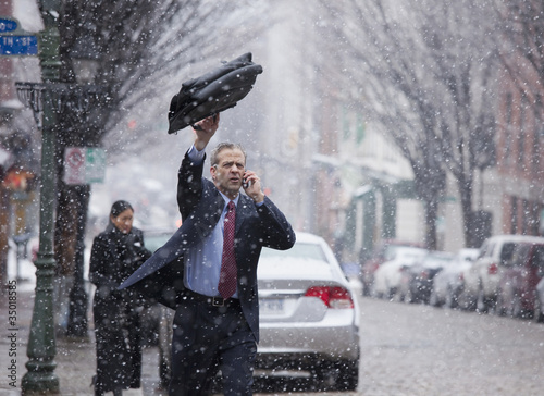 Photo: Caucasian businessman hailing taxi in snow Caucasian businessman hailing taxi in snow
