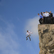 Businessman jumping off cliff while co-workers watch