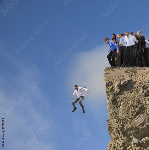 Photo: Businessman jumping off cliff while co-workers watch Businessman jumping off cliff while co-workers watch