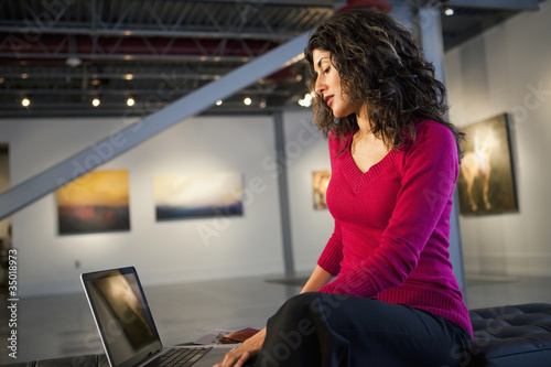 Photo: Ecuadorian businesswoman using laptop in art gallery Ecuadorian businesswoman using laptop in art gallery