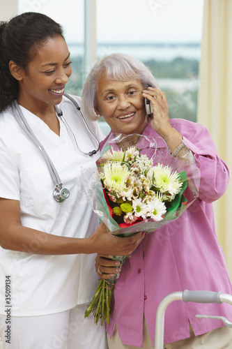 Photo: Nurse helping African American woman talking on cell phone Nurse helping African American woman talking on cell phone