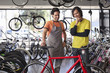 Foto: Bike shop owner helping customer choose bicycle Bike shop owner helping customer choose bicycle