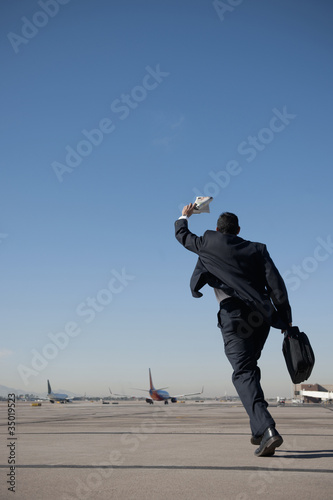 Photo: Hispanic businessman running on airport tarmac Hispanic businessman running on airport tarmac