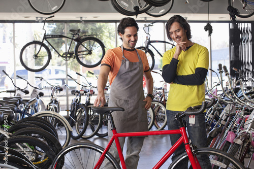 Photo: Bike shop owner helping customer choose bicycle Bike shop owner helping customer choose bicycle