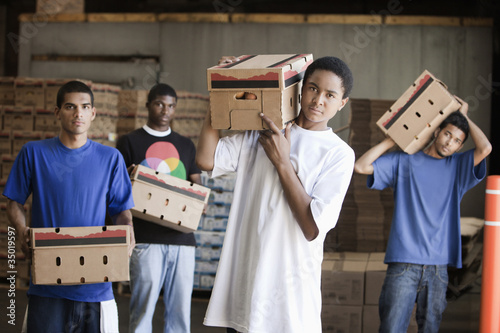 Photo: Men carrying cardboard boxes in warehouse Men carrying cardboard boxes in warehouse