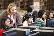Librarian helping students with research in school library