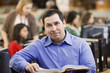 Mixed race man reading book in school library
