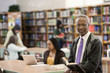 Black librarian reading book in school library