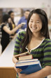 Asian student holding books in school library