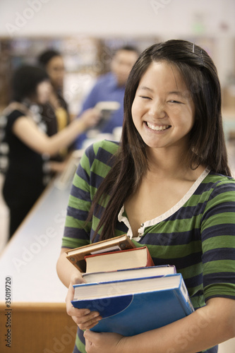 Photo: Asian student holding books in school library Asian student holding books in school library