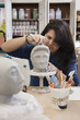 Hispanic student sculpting bust in classroom