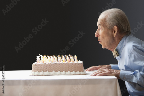 Photo: Senior Hispanic man blowing out birthday candles Senior Hispanic man blowing out birthday candles