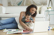 Mixed race woman holding baby and using laptop