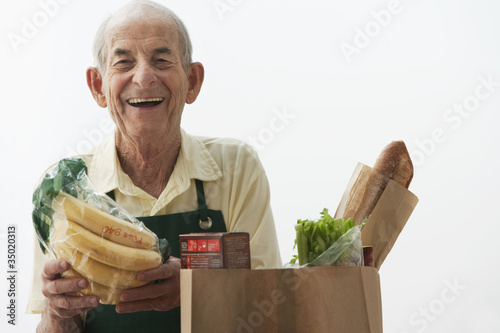 Photo: Senior Hispanic grocer loading paper bag with food Senior Hispanic grocer loading paper bag with food