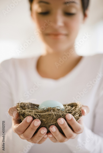 Photo: Mixed race woman holding nest with egg Mixed race woman holding nest with egg