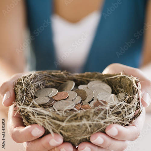 Photo: Mixed race woman holding nest filled with coins Mixed race woman holding nest filled with coins