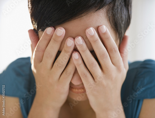 Foto: Mixed race woman covering face with hands Mixed race woman covering face with hands