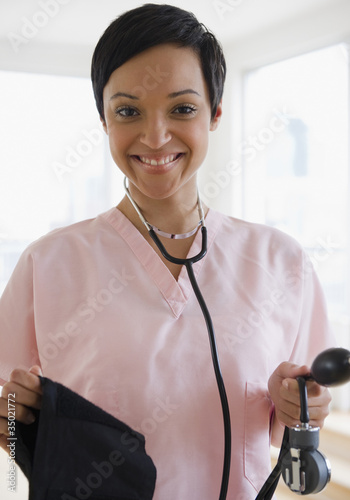 Photo: Mixed race doctor holding blood pressure gauge Mixed race doctor holding blood pressure gauge