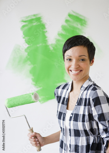 Photo: Mixed race woman holding paint roller with green paint Mixed race woman holding paint roller with green paint