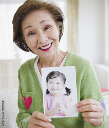 Photo: Japanese woman holding photograph of girl Japanese woman holding photograph of girl