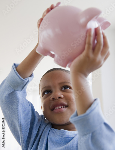Photo: African American boy lifting piggy bank African American boy lifting piggy bank