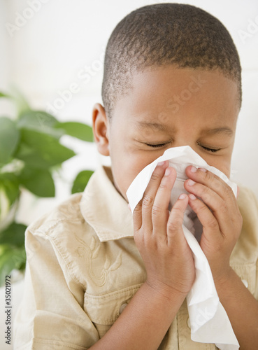 Photo: African American boy sneezing into tissue African American boy sneezing into tissue