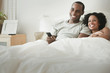 Couple laying in bed watching television