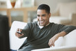 Mixed race man sitting on sofa watching television