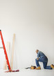 African American construction worker kneeling to look at wall
