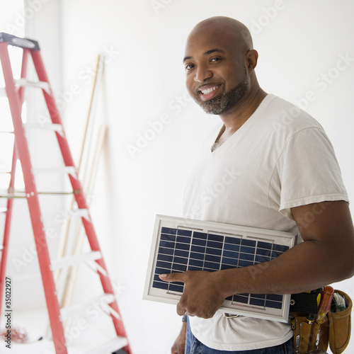 Photo: African American construction worker carrying solar panel African American construction worker carrying solar panel