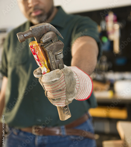 Photo: "African American carpenter holding screwdriver, wrench and hammer" "African American carpenter holding screwdriver, wrench and hammer"