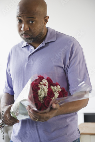 Photo: Sad African American man holding bouquet of roses Sad African American man holding bouquet of roses