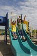 Black mother and son sliding on slide in park