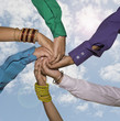 People holding hands together against blue sky