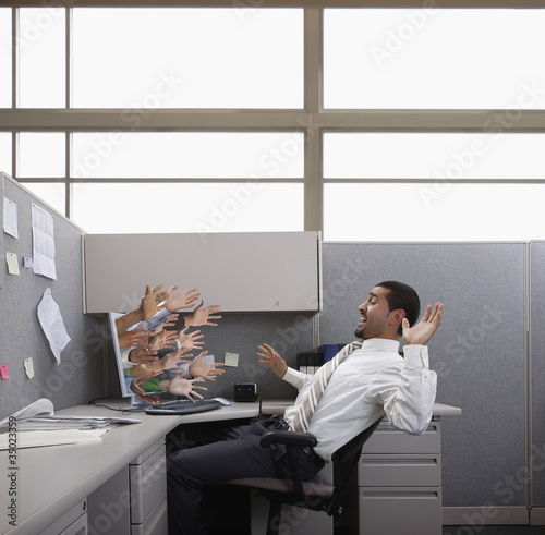 Photo: Hands reaching out from computer trying to grab Hispanic businessman Hands reaching out from computer trying to grab Hispanic businessman