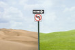 Road signs pointing at green grass and desert