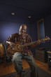 African American man playing guitar in studio