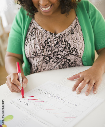 Photo: African American woman crossing off days on calendar African American woman crossing off days on calendar