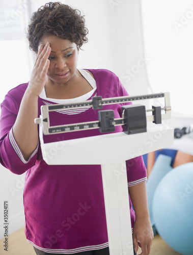 Foto: African American woman weighing herself African American woman weighing herself