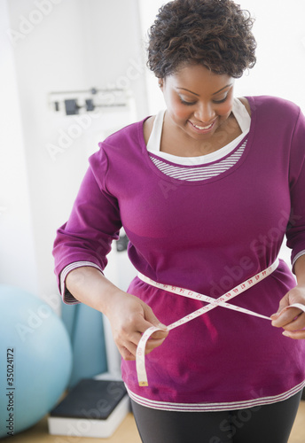 Photo: African American woman measuring her waist African American woman measuring her waist
