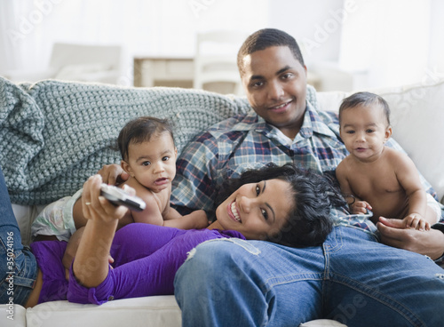 Photo: Parents and twin baby boys watching television together Parents and twin baby boys watching television together