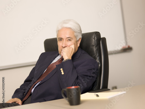 Photo: Hispanic businessman sitting at desk Hispanic businessman sitting at desk