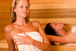 Sauna two women relaxing sweating covered towel
