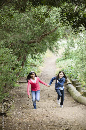 Photo: Girls holding hands and running on path Girls holding hands and running on path