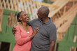 Smiling Black couple outside house under construction
