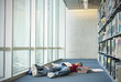 Books surrounding exhausted Hispanic student laying on library floor