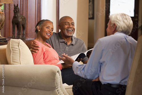 Photo: Financial advisor meeting with couple in living room Financial advisor meeting with couple in living room