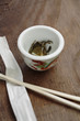 Close up of tea leaves in cup next to chopsticks