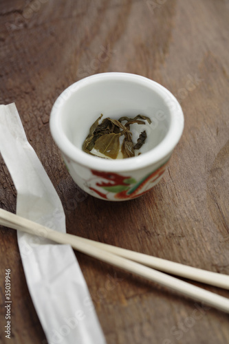 Photo: Close up of tea leaves in cup next to chopsticks Close up of tea leaves in cup next to chopsticks